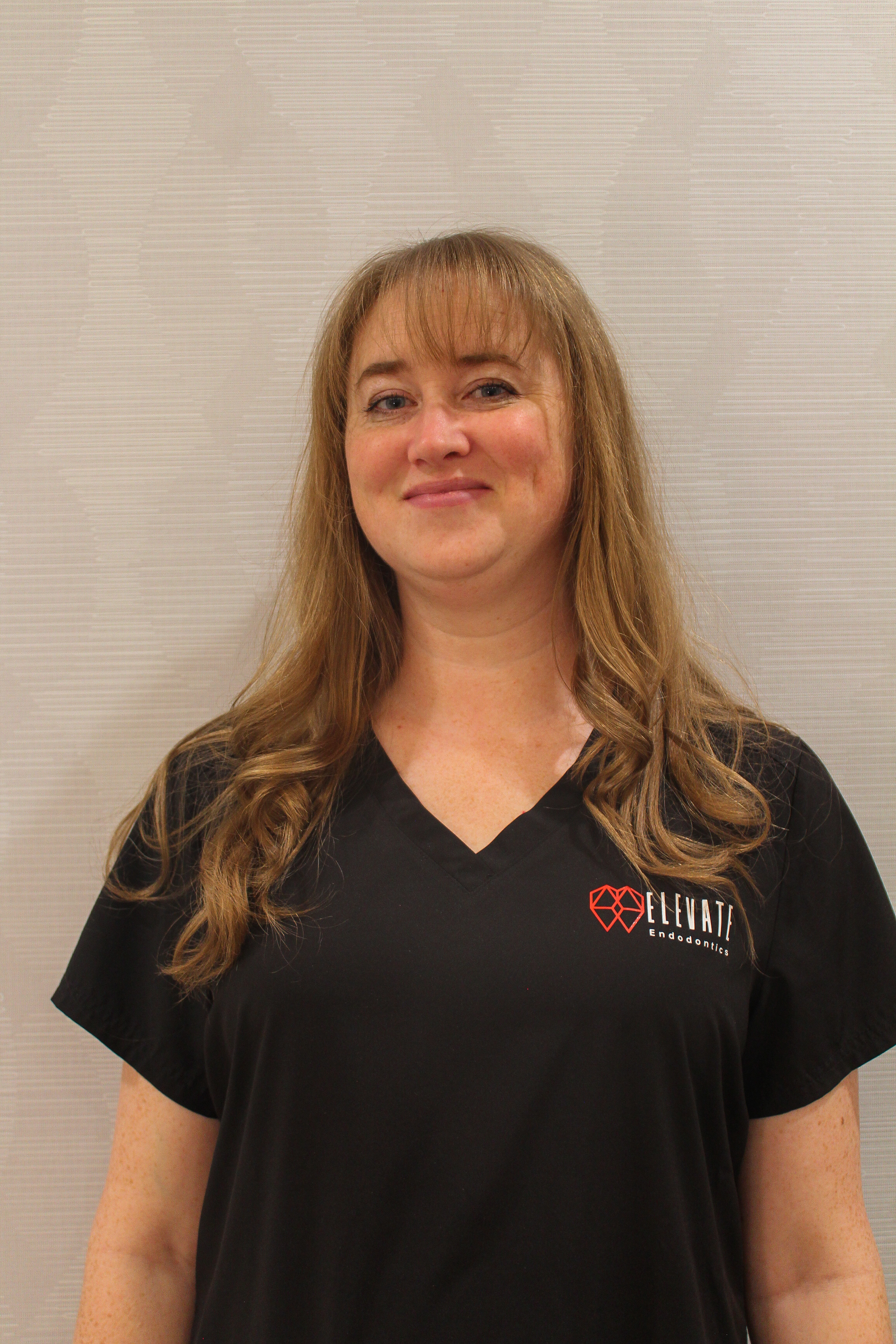 Kris assistant office manager at Elevate Endo Smiling in black scrubs